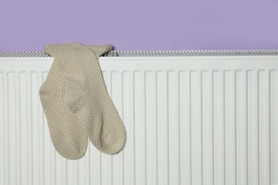 Photo of Beige socks on heating radiator near violet wall