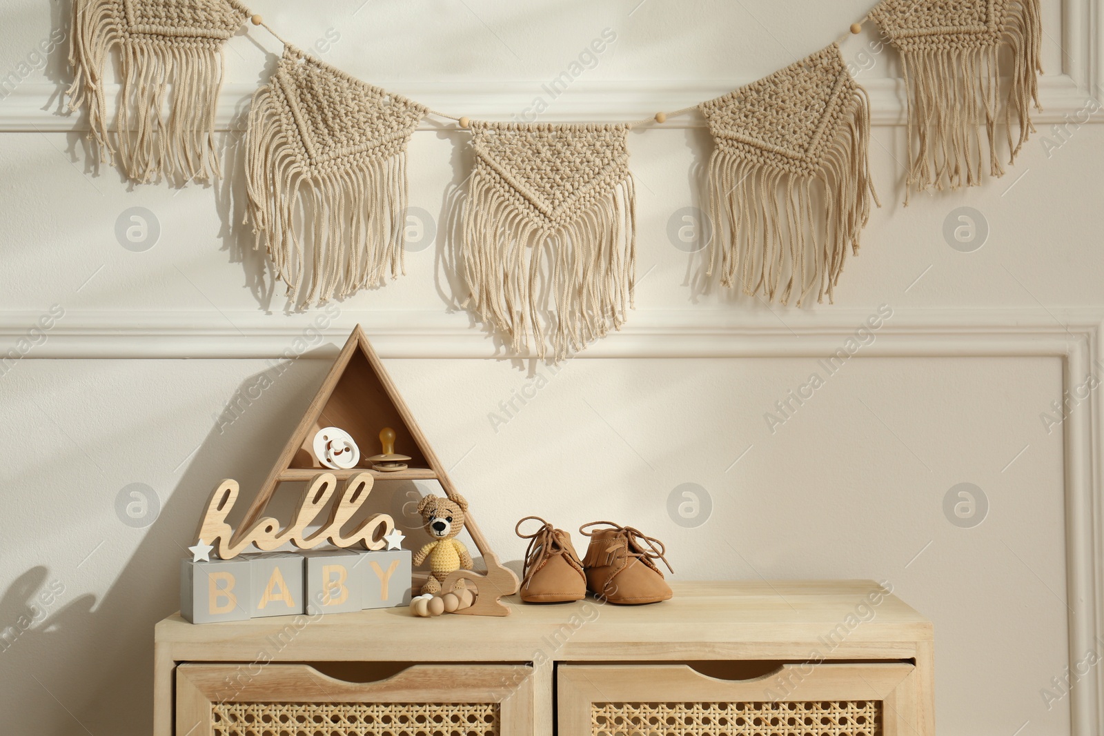 Photo of Different baby accessories and toys on wooden cabinet in child room. Interior design