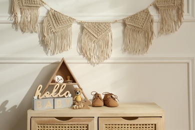 Different baby accessories and toys on wooden cabinet in child room. Interior design