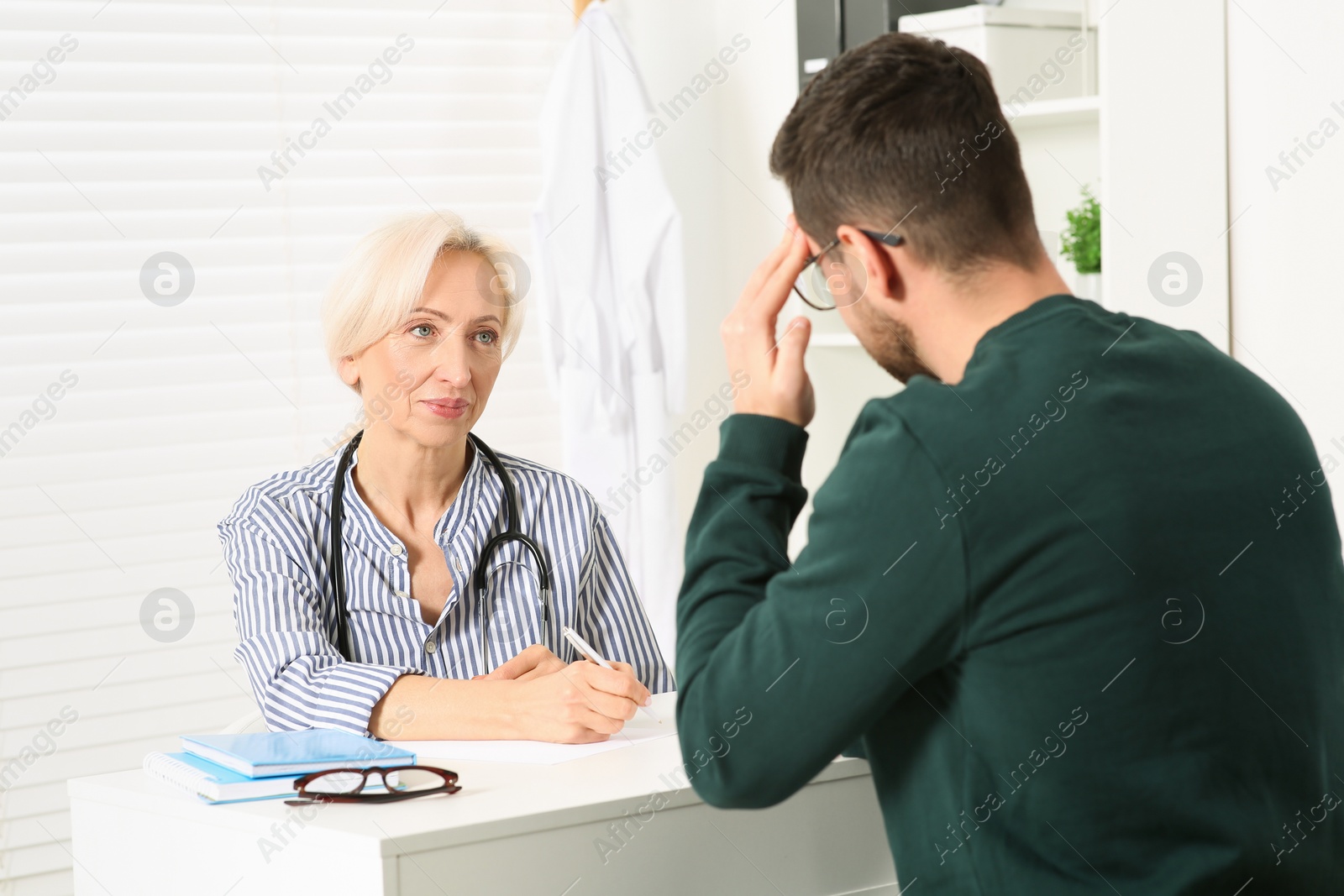 Photo of Doctor consulting patient at white table in clinic