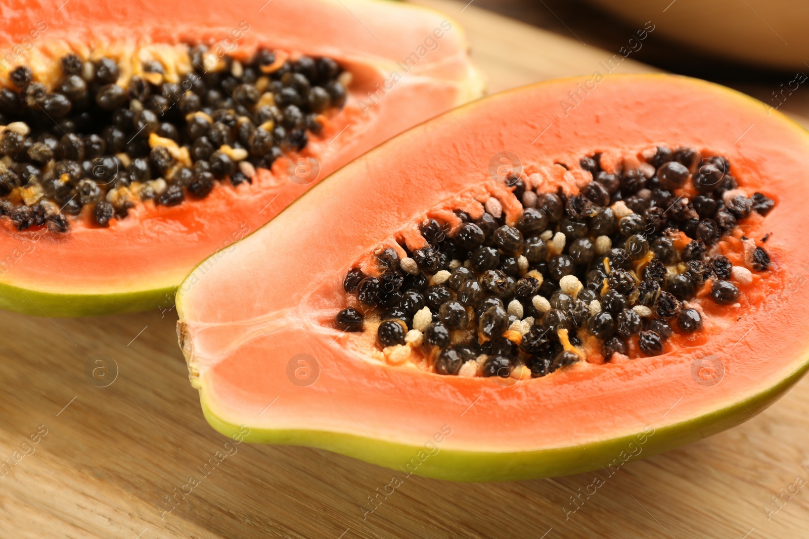 Photo of Fresh halved papaya fruit on wooden board, closeup