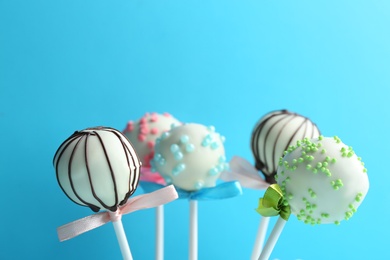 Photo of Tasty cake pops with bows on light blue background