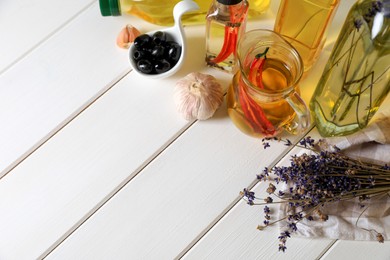 Different cooking oils and ingredients on white wooden table, above view. Space for text