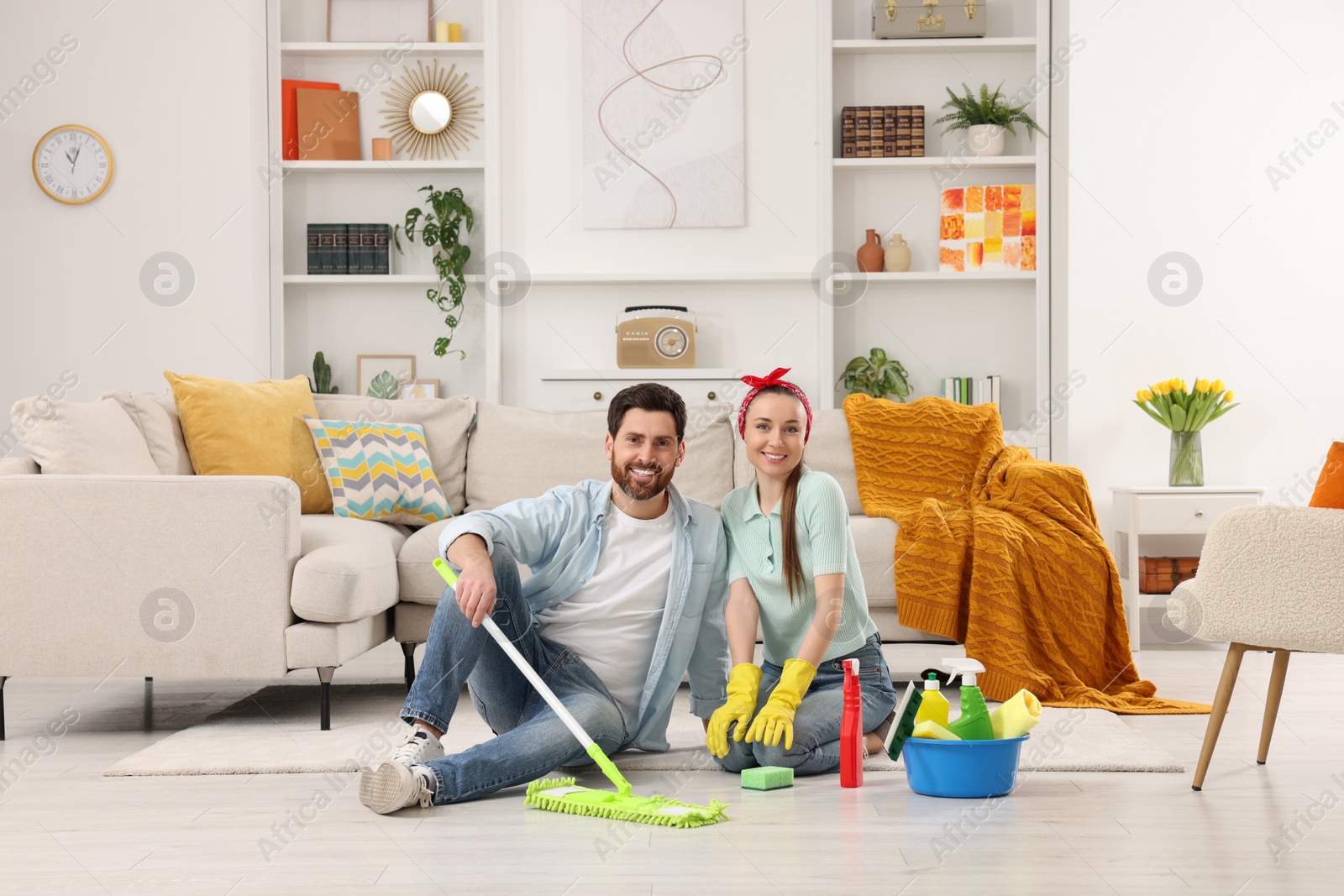 Photo of Spring cleaning. Couple with detergents and mop in living room