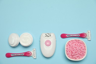 Photo of Flat lay composition with epilator and other hair removal products on light blue background. Space for text