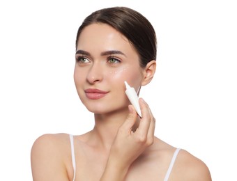 Photo of Young woman applying cream under eye on white background