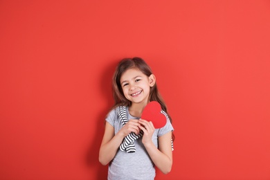 Portrait of girl with paper heart on color background