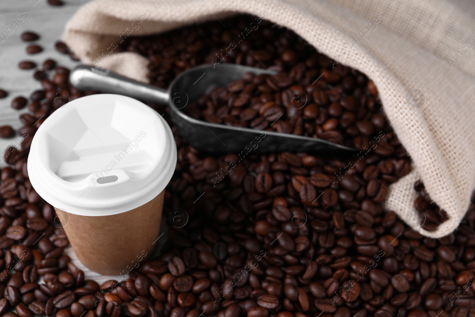 Photo of Coffee to go. Paper cup, roasted beans and scoop on table, space for text