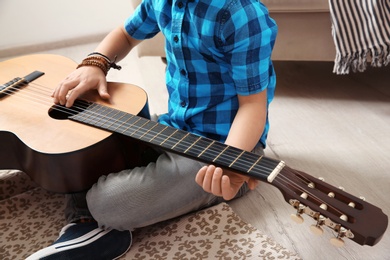 Little boy playing guitar on floor, closeup