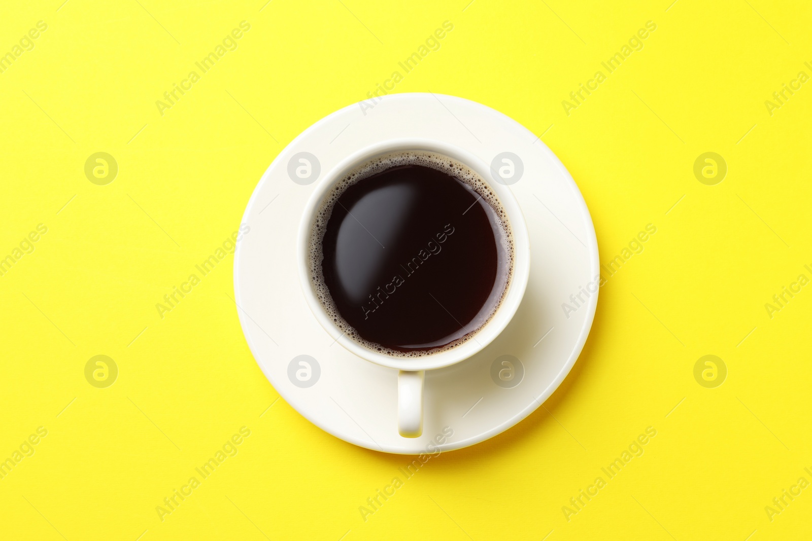 Photo of Cup of aromatic coffee on yellow background, top view