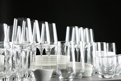 Set of empty glasses and dishware on table against black background