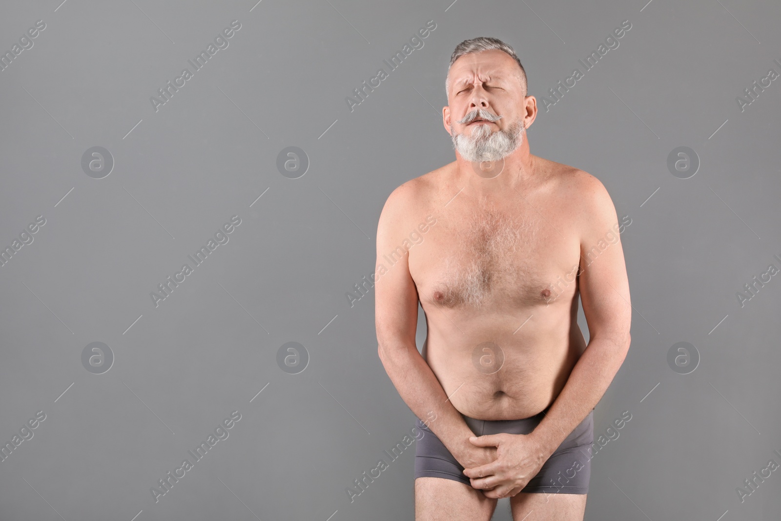 Photo of Mature man with urological problems suffering from pain on grey background