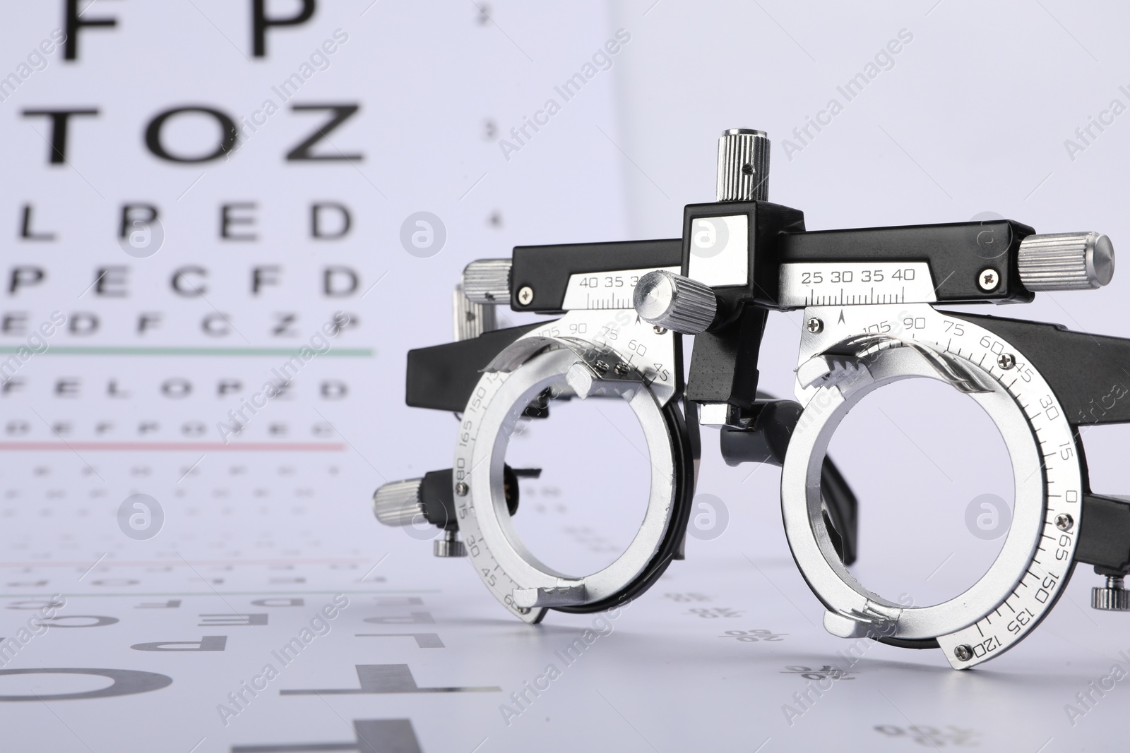Photo of Vision test chart and trial frame on white background, closeup
