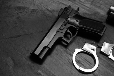 Photo of Gun and handcuffs on dark table, space for text