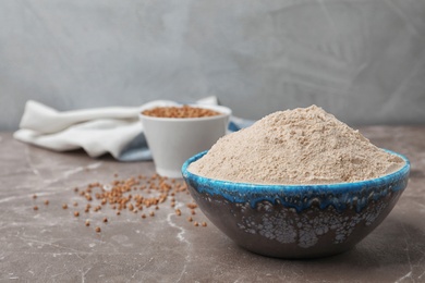 Photo of Bowl with buckwheat flour on table