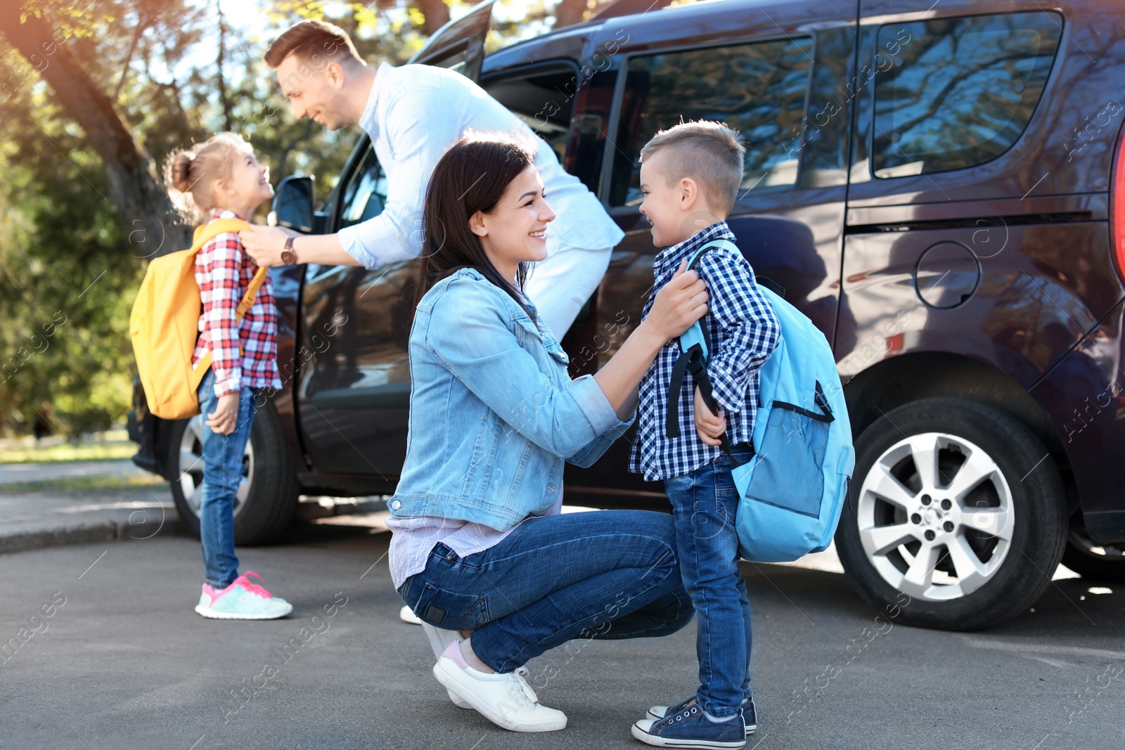 Photo of Young parents saying goodbye to their little children near school