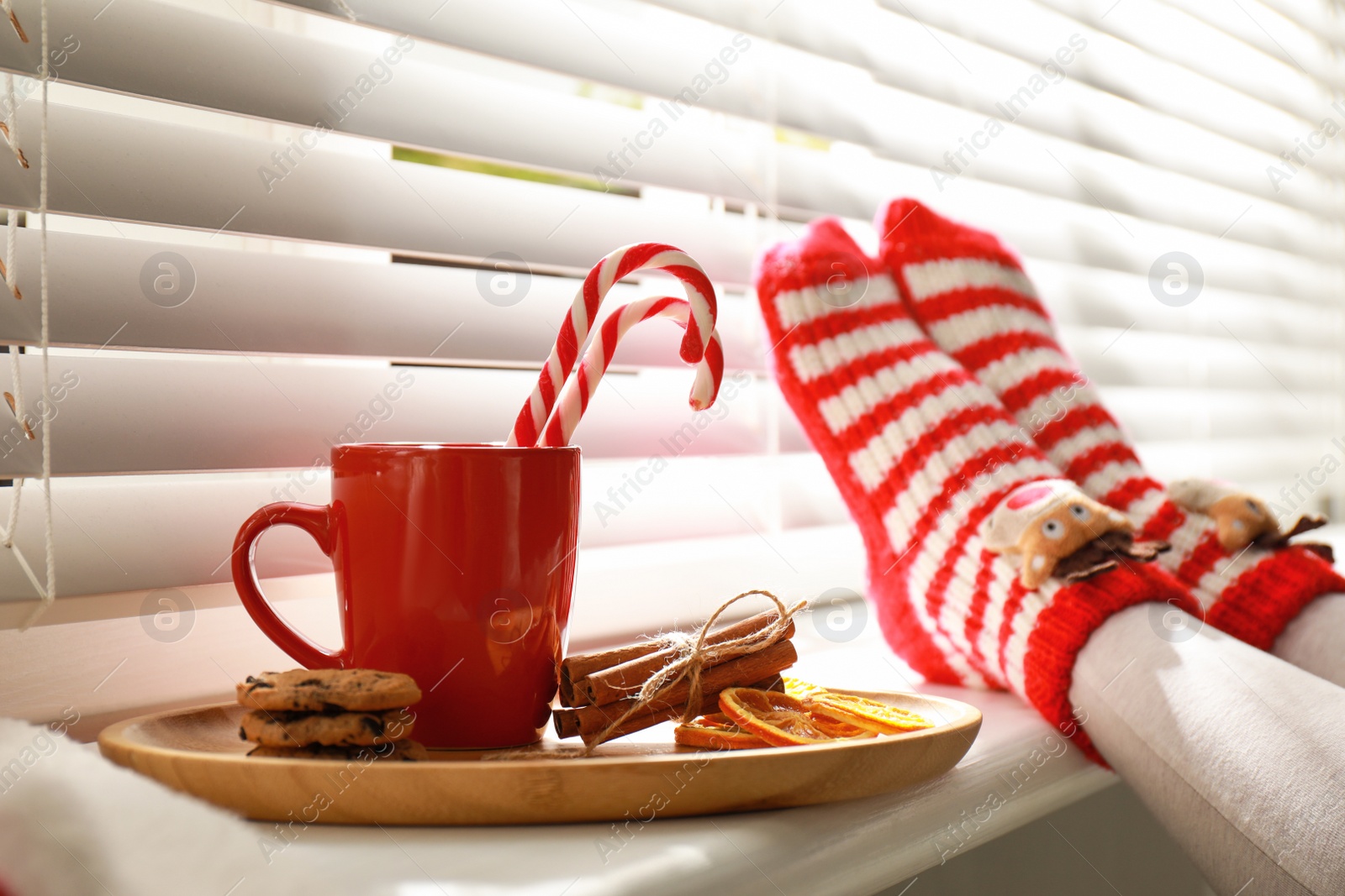 Photo of Woman and cup of hot winter drink near window indoors, closeup