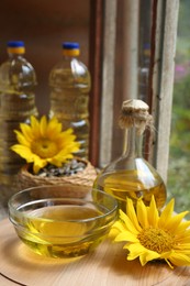 Photo of Organic sunflower oil and flower on wooden table, closeup