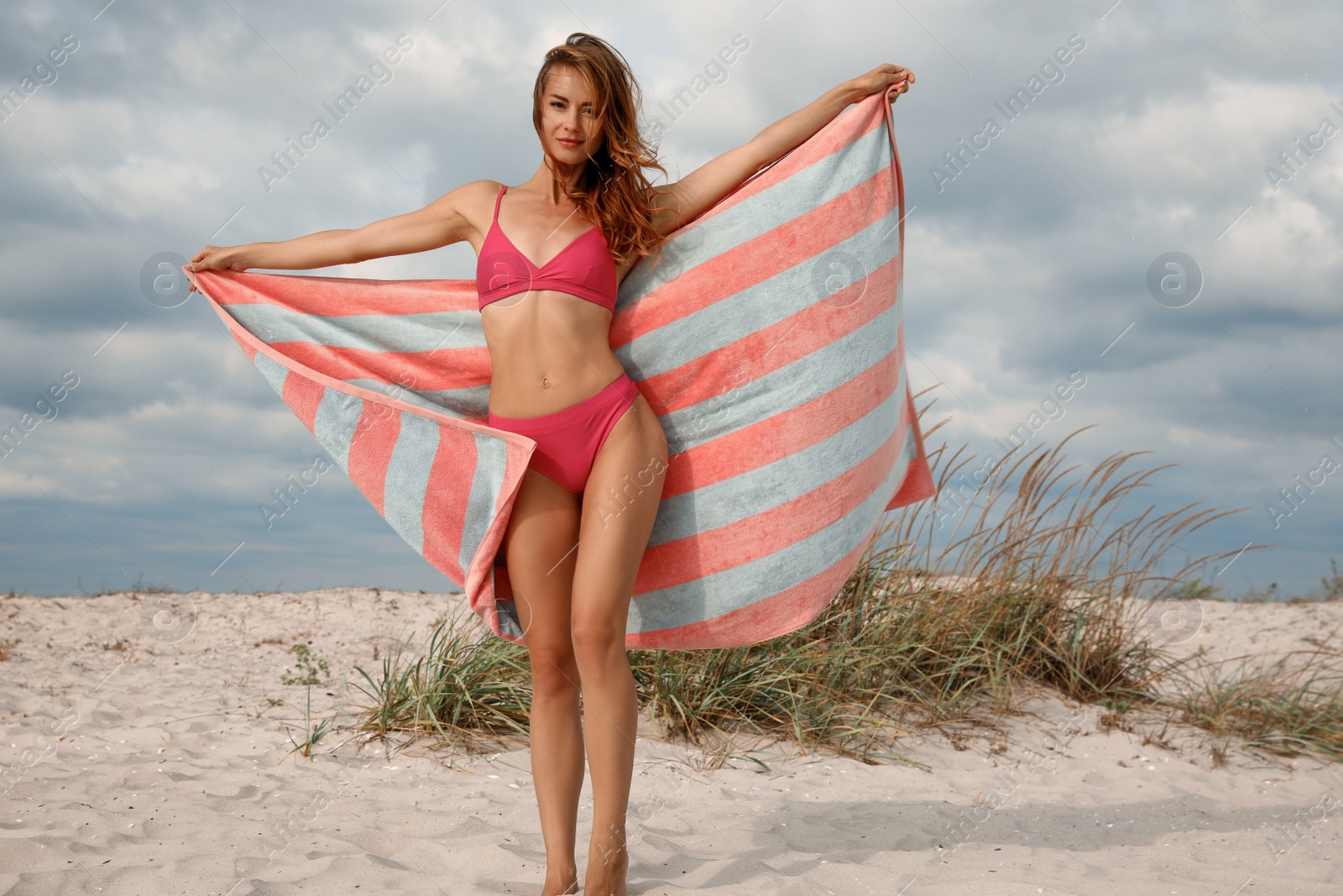 Photo of Beautiful woman in bikini with beach towel on sand