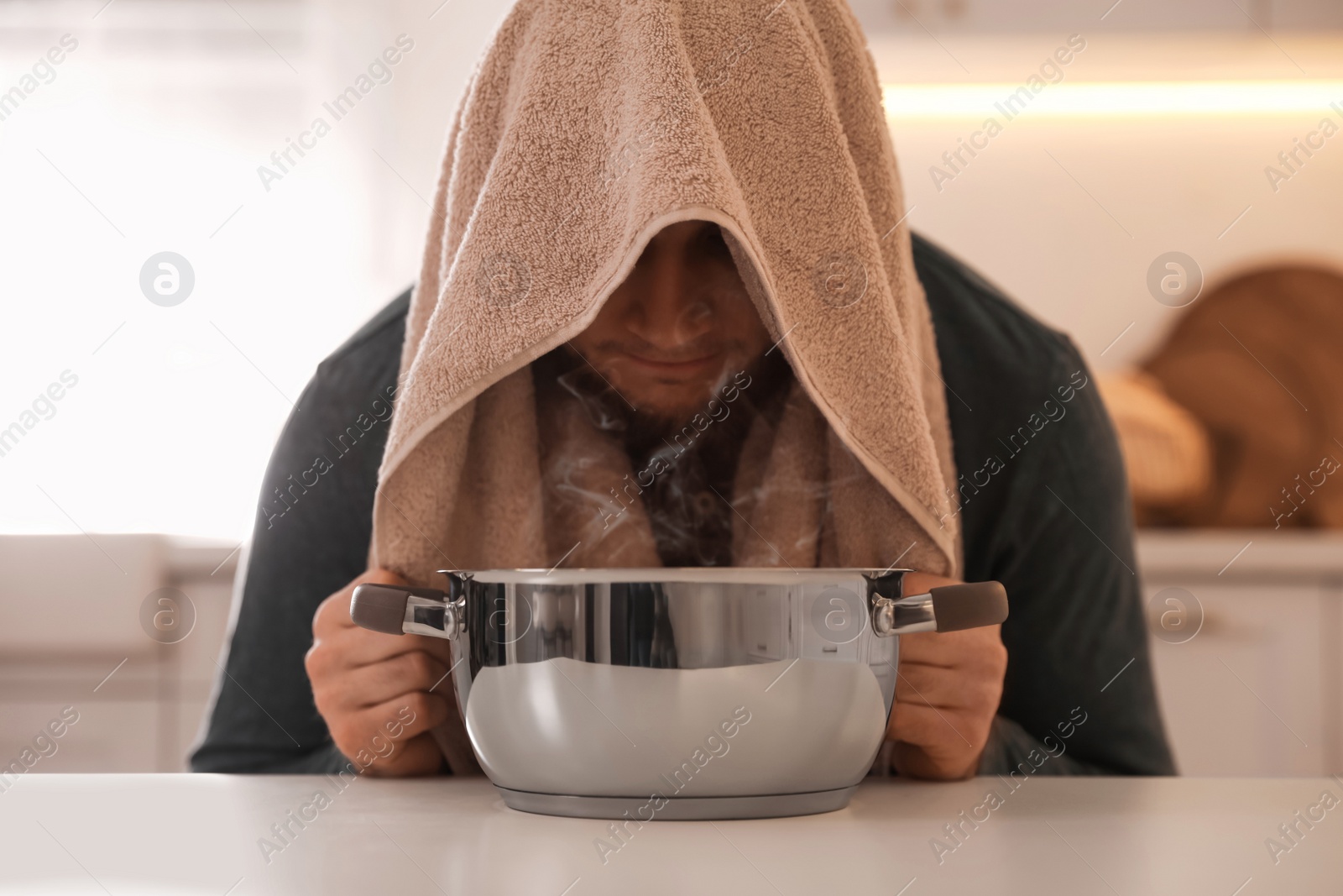 Photo of Man taking treatments at table indoors. Steam inhalation