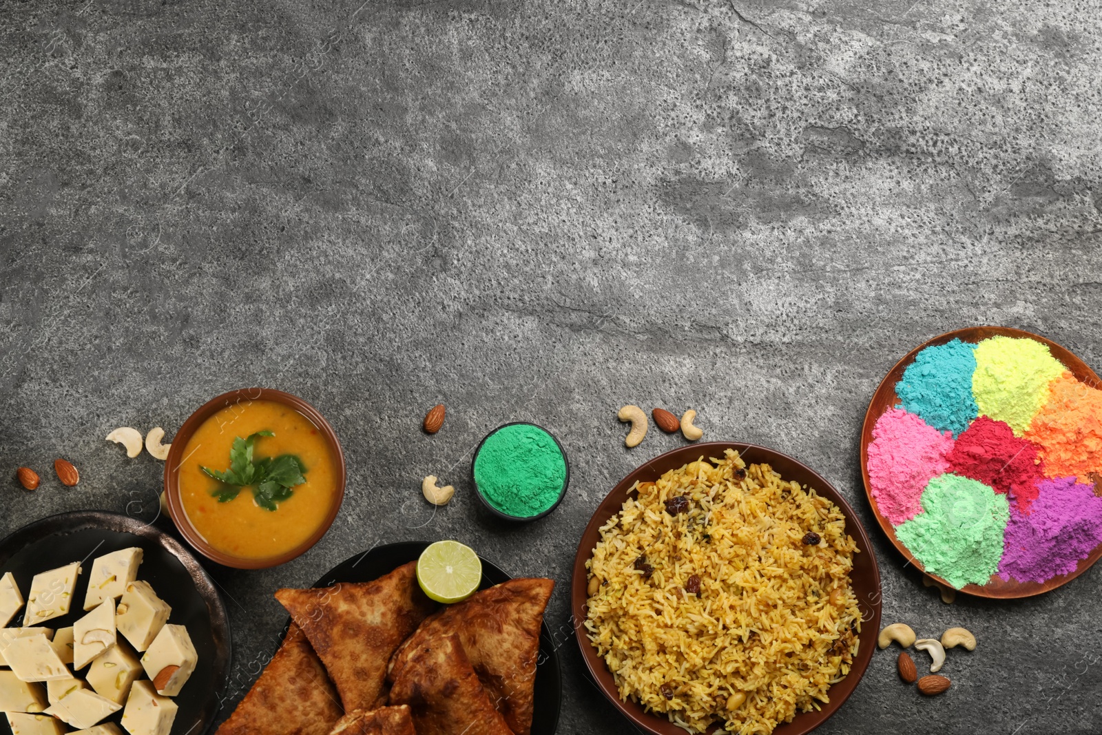 Photo of Traditional Indian food and color powders on grey table, flat lay with space for text. Holi festival celebration