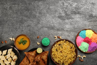 Photo of Traditional Indian food and color powders on grey table, flat lay with space for text. Holi festival celebration