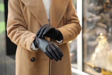 Woman putting on stylish leather gloves outdoors, closeup of hands