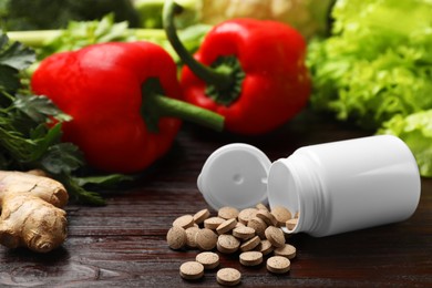 Dietary supplements. Overturned bottle, pills and food products on wooden table, closeup