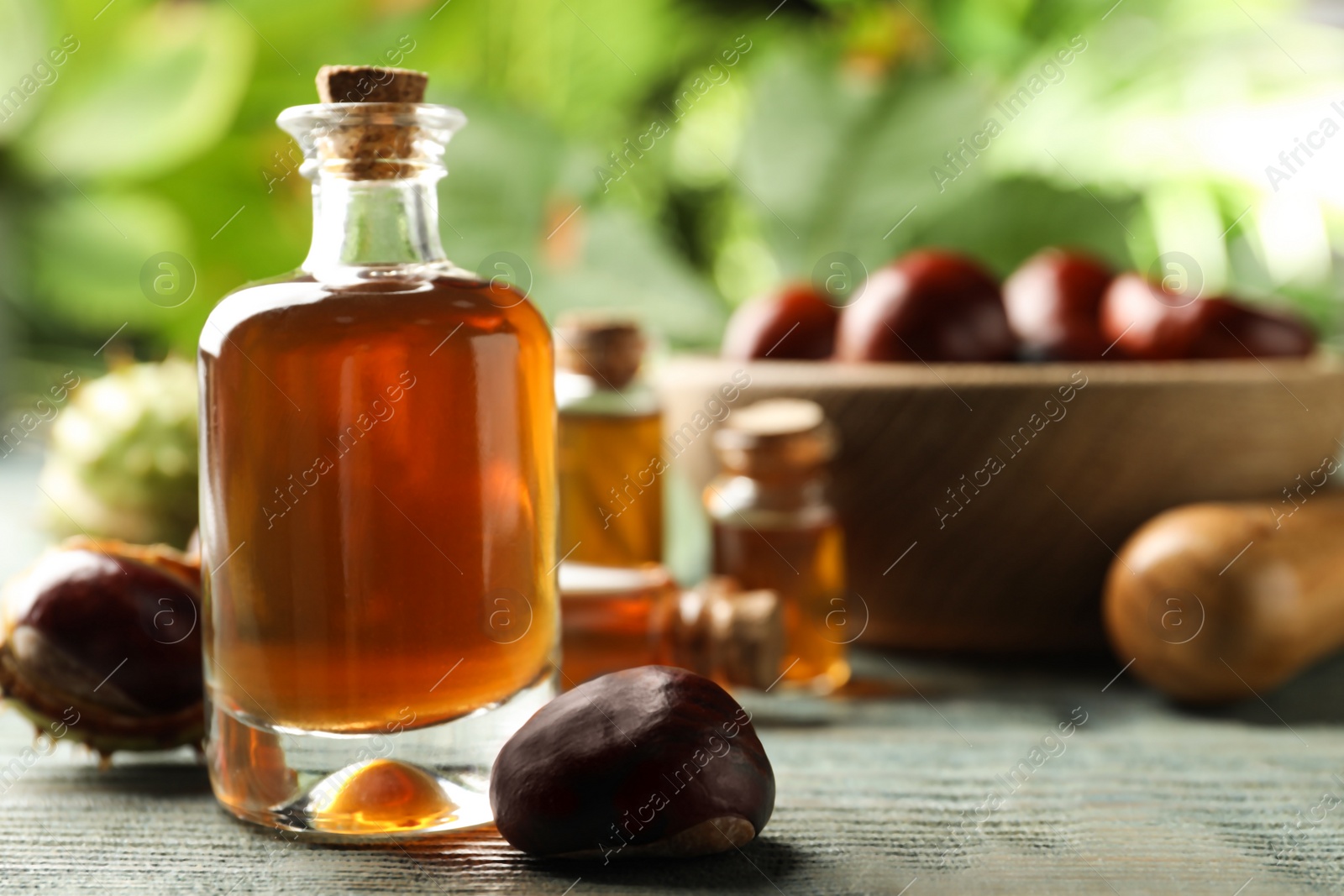 Photo of Chestnuts and bottle of essential oil on blue wooden table. Space for text