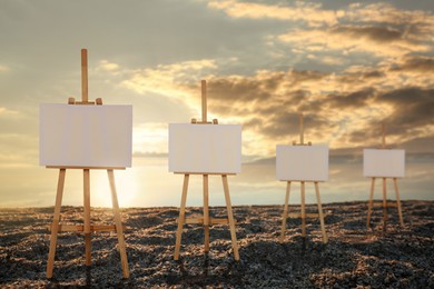 Wooden easels with blank canvases on beach near sea at sunrise 