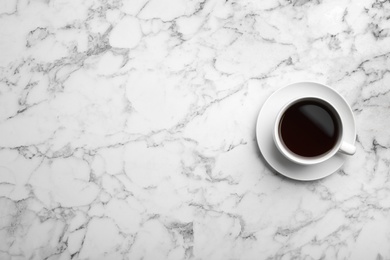 Ceramic cup with hot aromatic coffee on marble background, top view