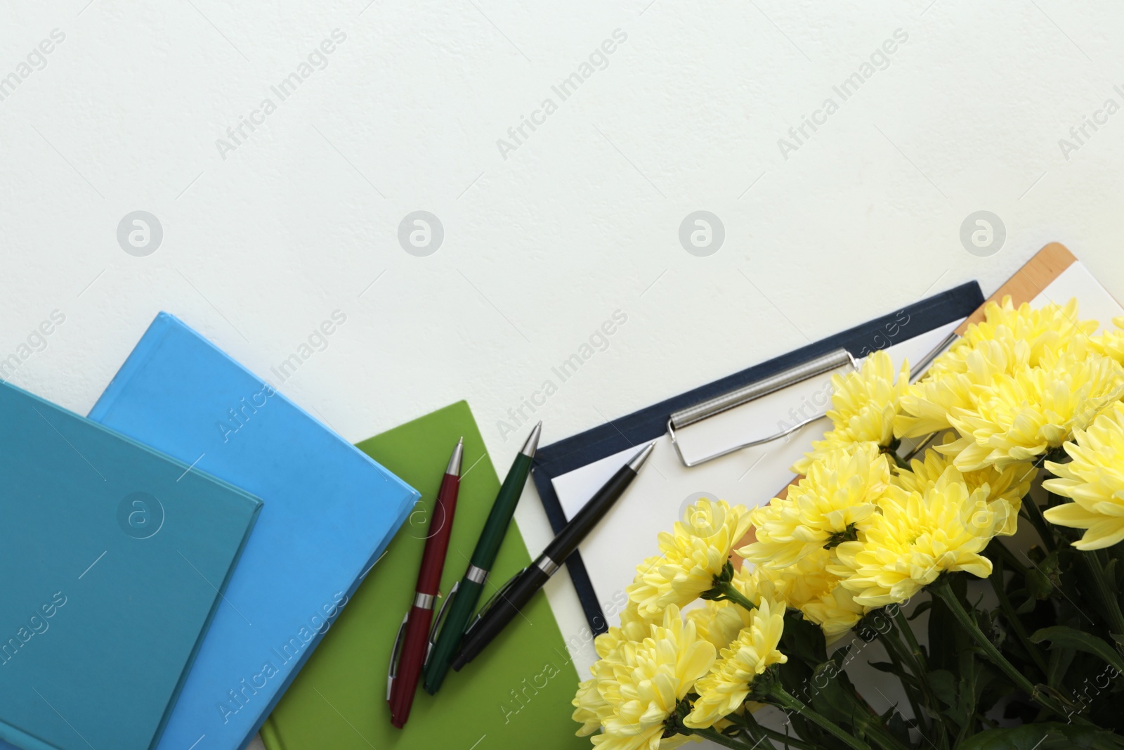 Photo of Beautiful flowers and stationery on white background, flat lay with space for text. Teacher's Day