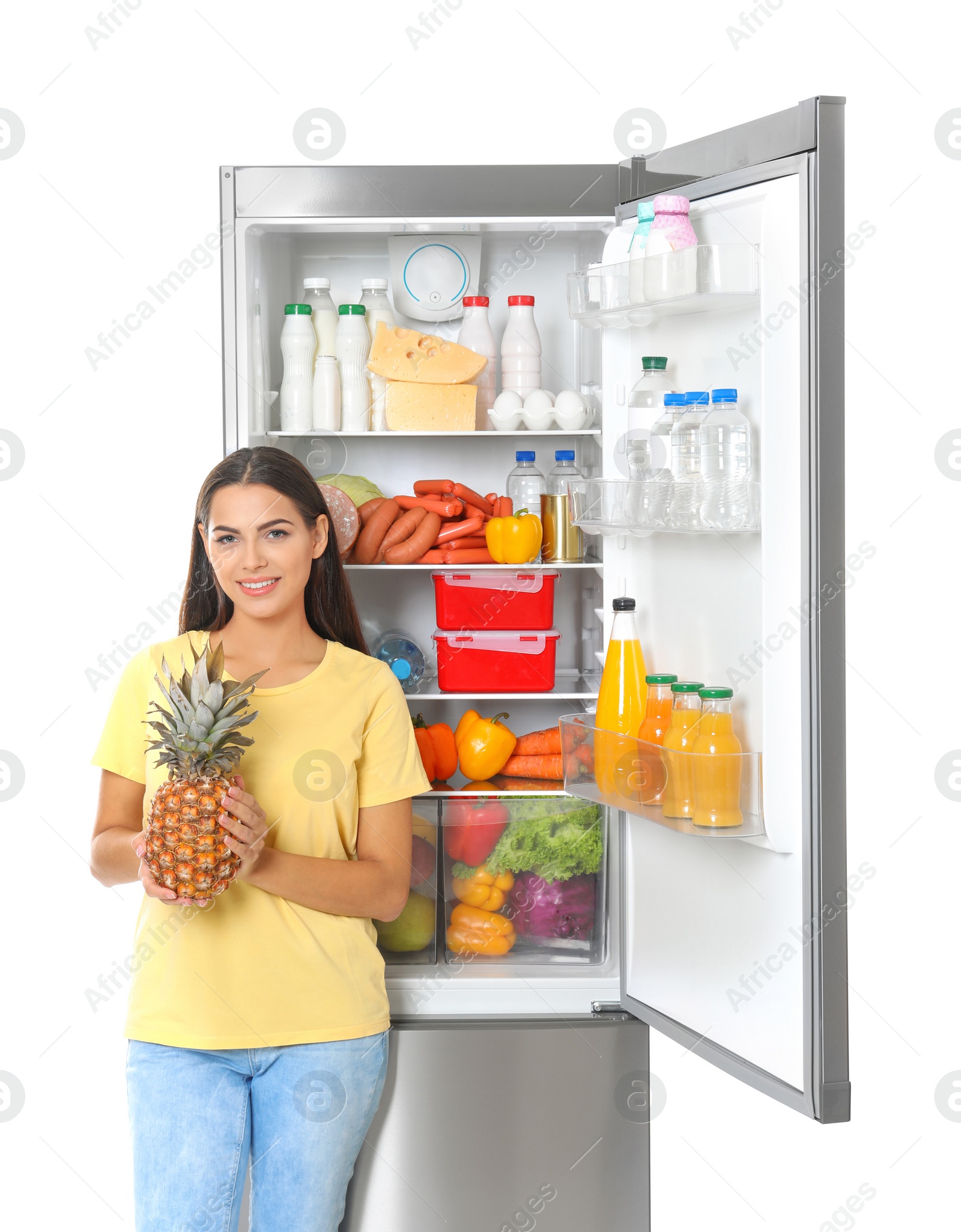 Photo of Young woman with pineapple near open refrigerator on white background