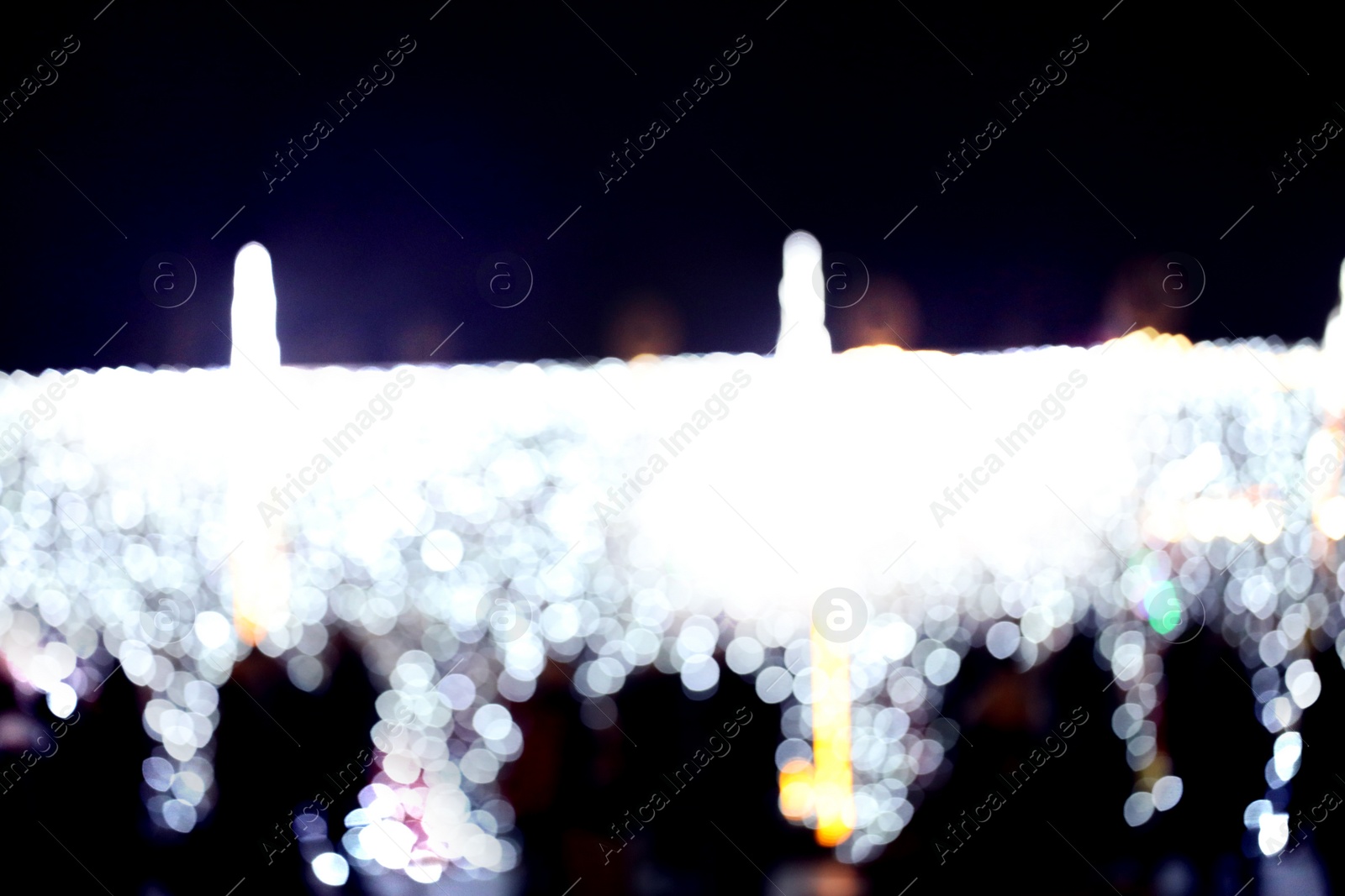 Photo of Blurred view of city street with festive lights at night. Bokeh effect