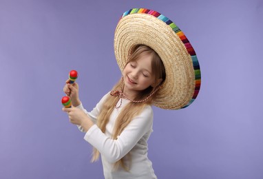 Cute girl in Mexican sombrero hat dancing with maracas on purple background