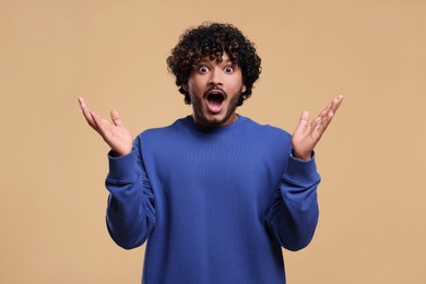 Handsome surprised man on beige background. Space for text