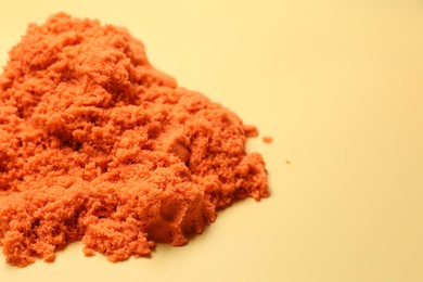Photo of Pile of orange kinetic sand on beige background, space for text