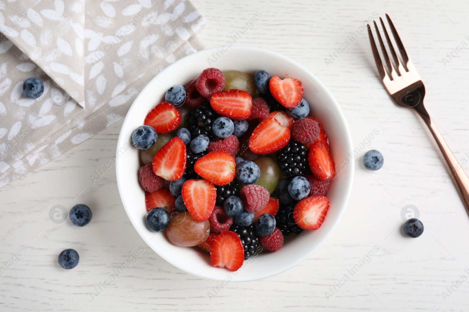 Photo of Fresh tasty fruit salad on white wooden table, flat lay