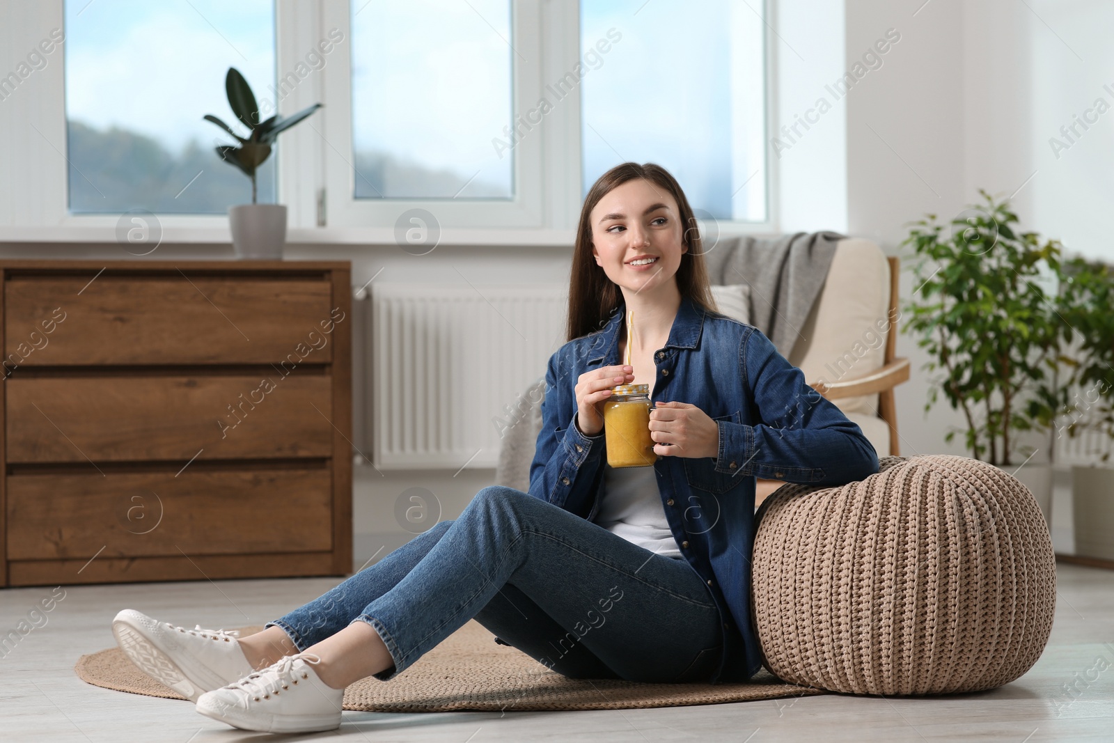 Photo of Beautiful young woman with delicious smoothie on floor at home. Space for text