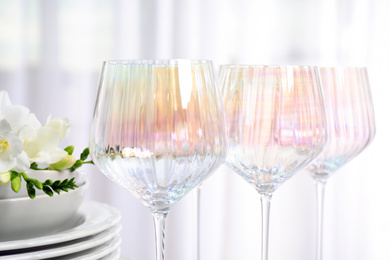 Set of glasses and dishes with flowers on light background, closeup