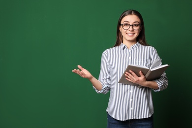 Photo of Portrait of young teacher with book on green background. Space for text
