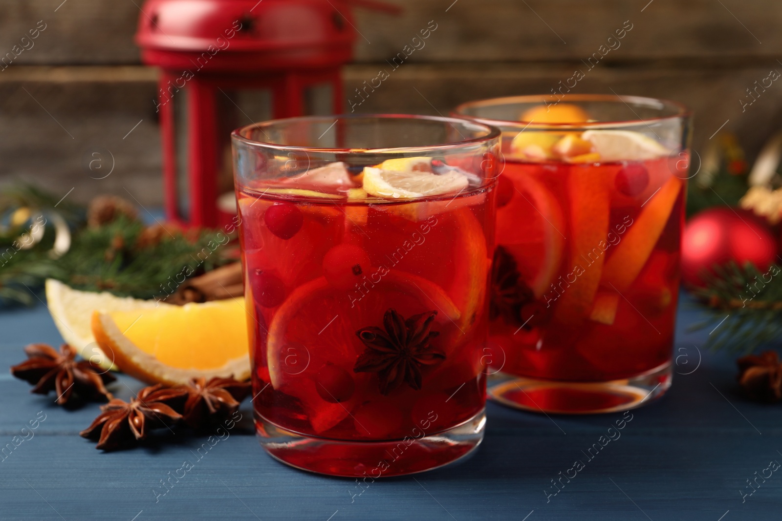 Photo of Delicious punch drink with cranberries and orange on blue wooden table