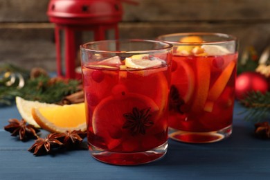 Photo of Delicious punch drink with cranberries and orange on blue wooden table