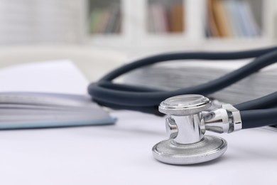 Stethoscope and blurred view of open book on background, closeup with space for text. Medical education