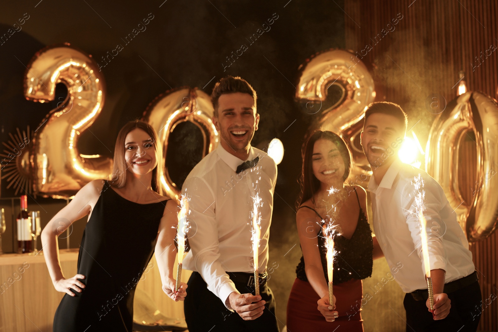 Photo of Young people celebrating New Year in club. Golden 2020 balloons on background