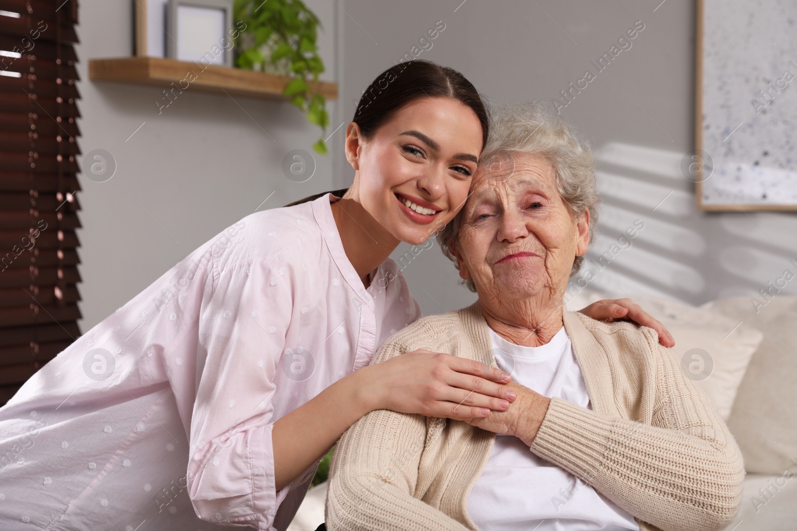 Photo of Portrait of young caregiver and senior woman indoors. Home care service