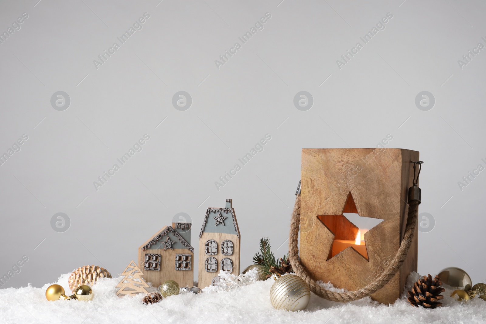 Photo of Composition with wooden Christmas lantern on snow against light grey background, space for text