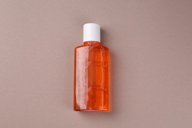 Photo of Fresh mouthwash in bottle on beige background, top view