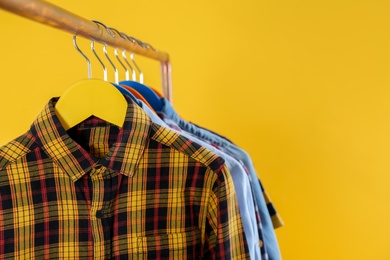 Photo of Rack with stylish children clothes on yellow background, closeup. Space for text