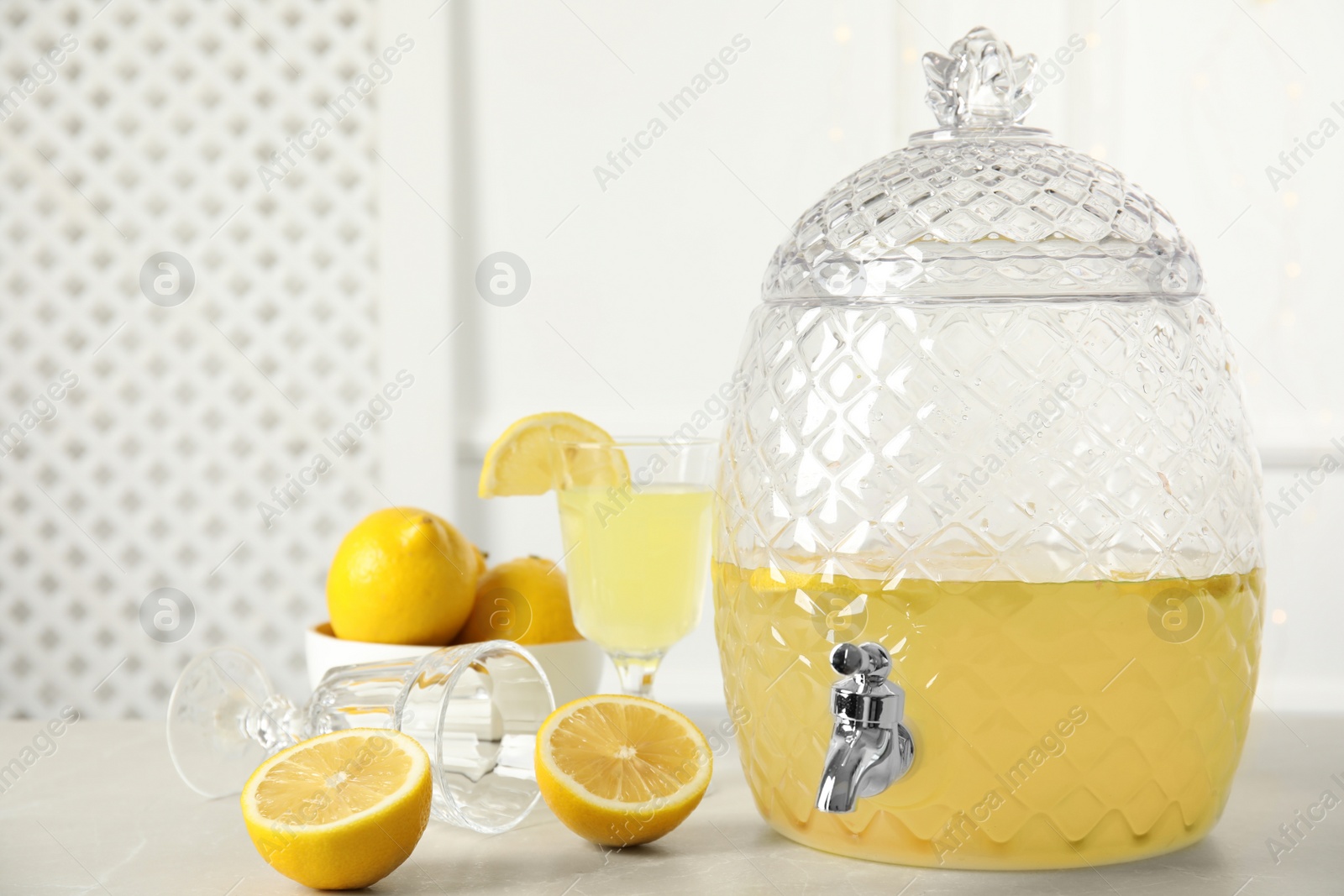 Photo of Beverage dispenser with delicious lemonade on light table. Space for text